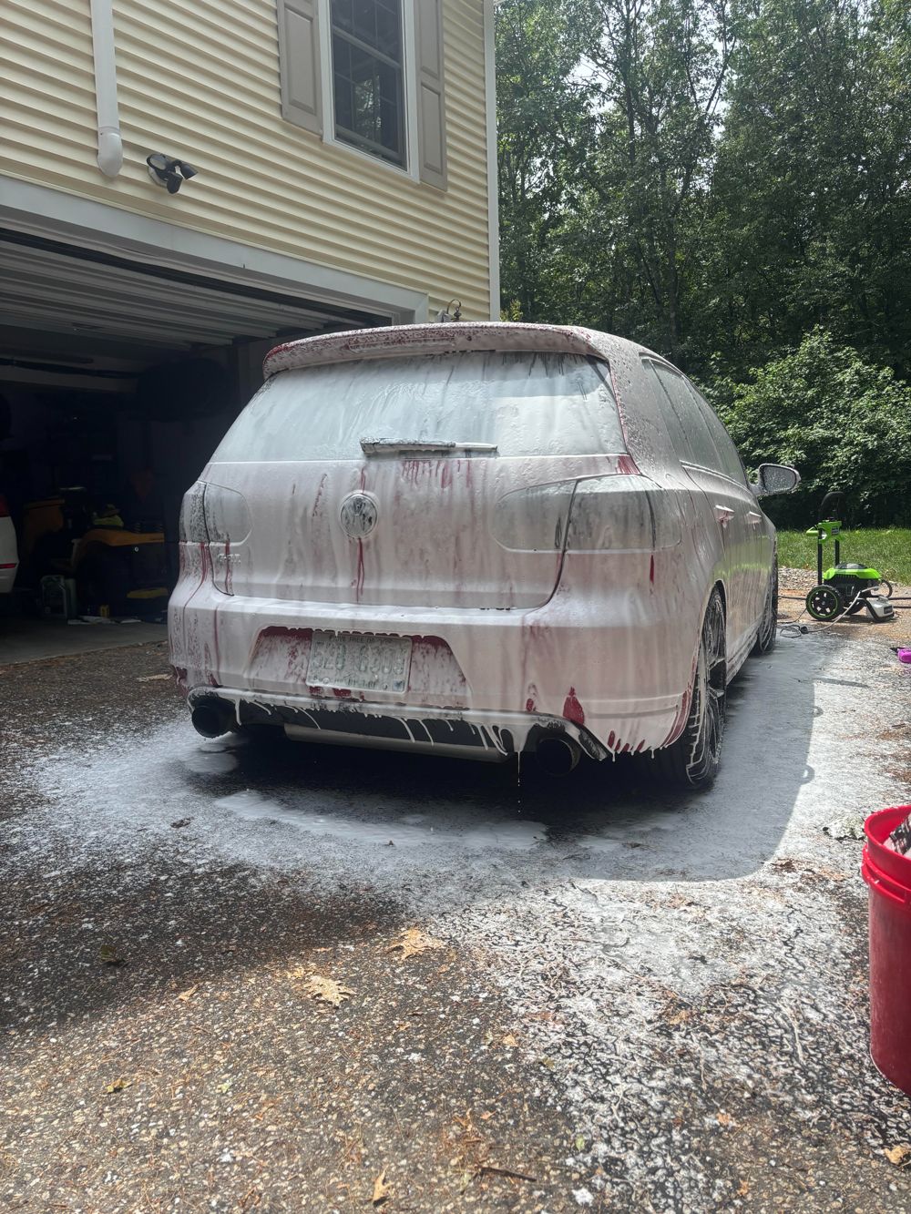 Volkswagen covered in pre-wash foam in a customer's driveway